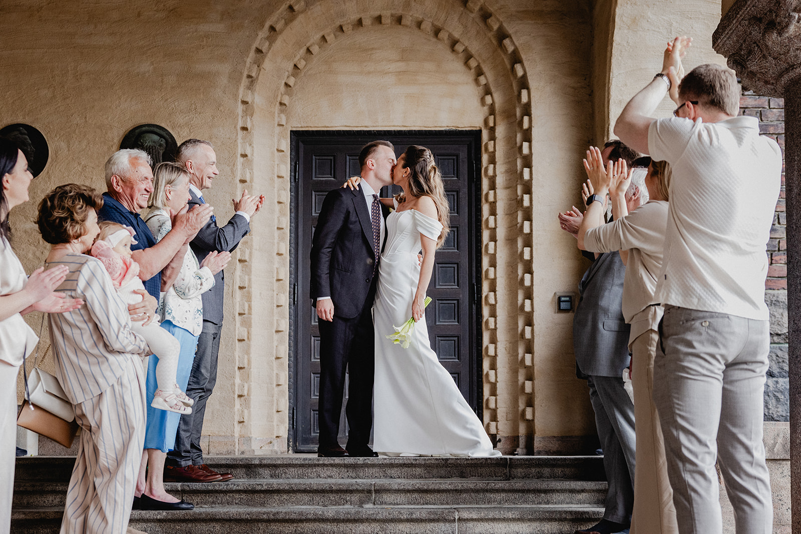 Gintare and Mikael kissing as guests applaud their wedding exit at Stockholm City Hall.