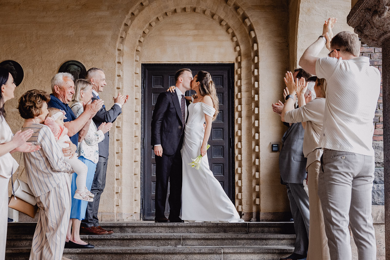 Gintare and Mikael kissing as guests applaud their wedding exit at Stockholm City Hall.