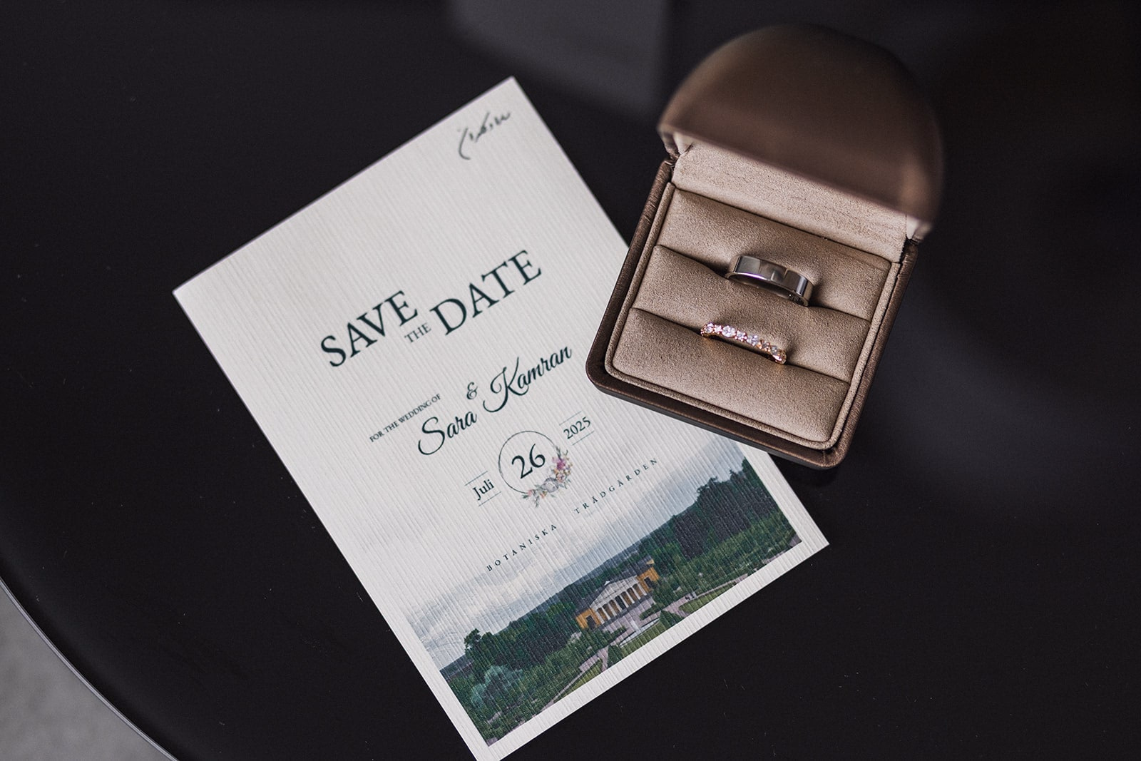 Wedding rings arranged beside Sara and Kamran’s invitation.