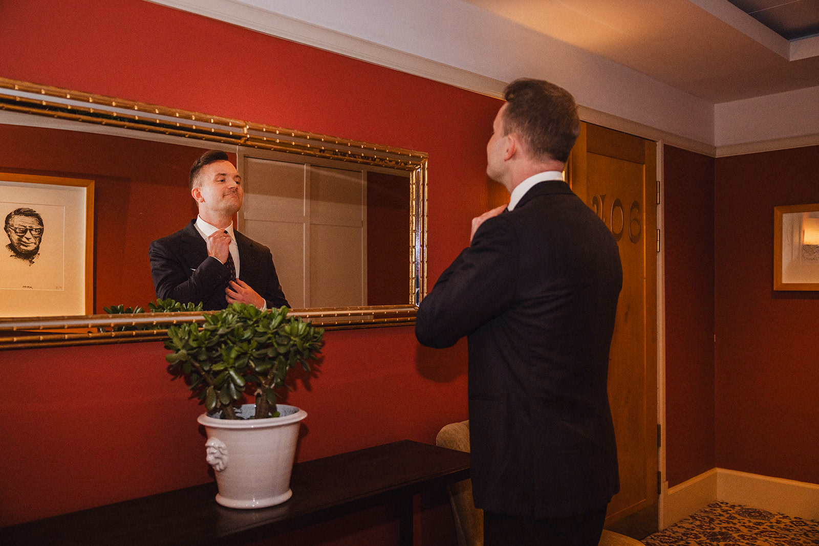 The groom checking his suit in a mirror during preparations at Hotel Diplomat.
