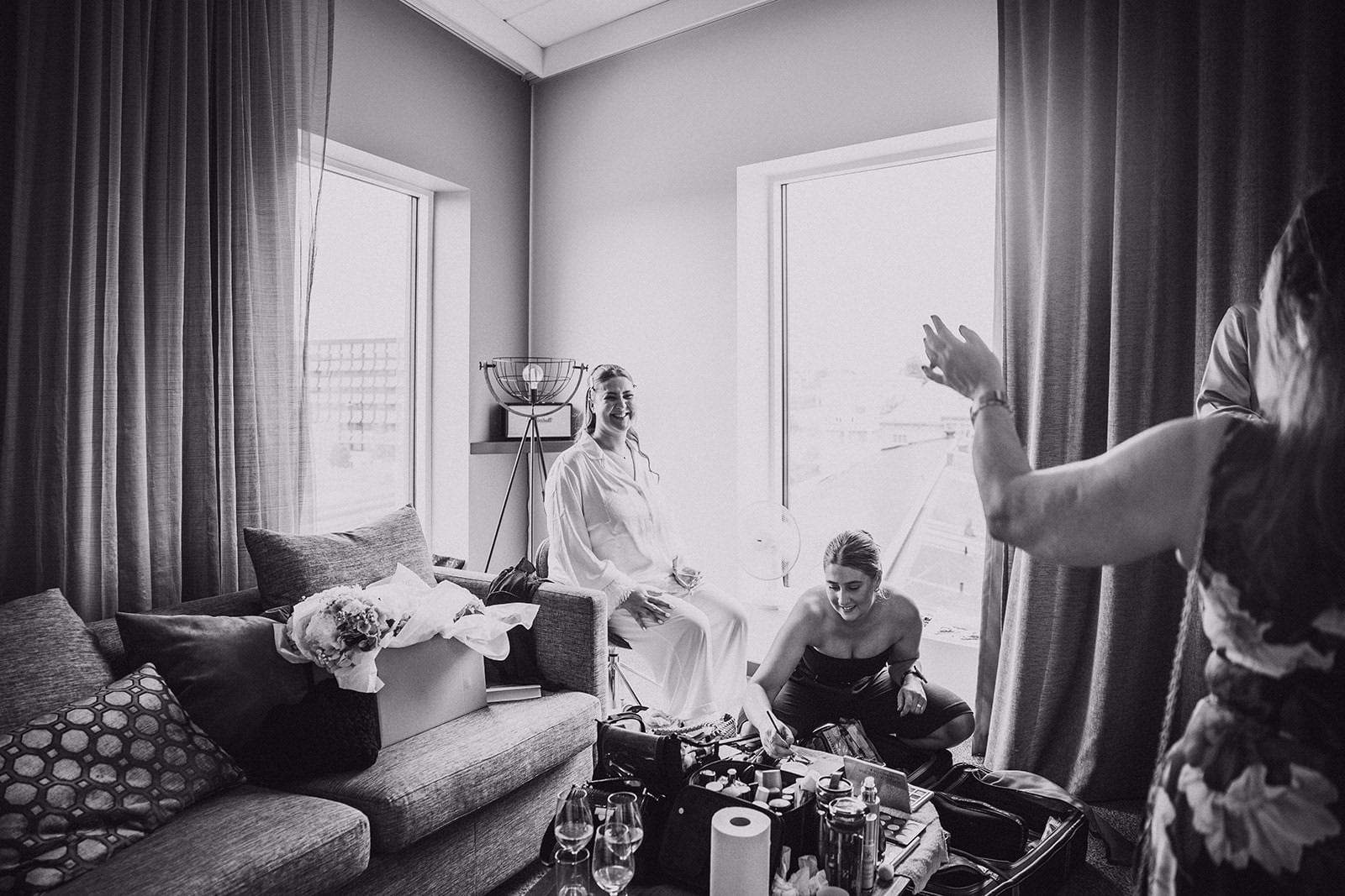 Friends preparing together in a hotel room before the wedding.
