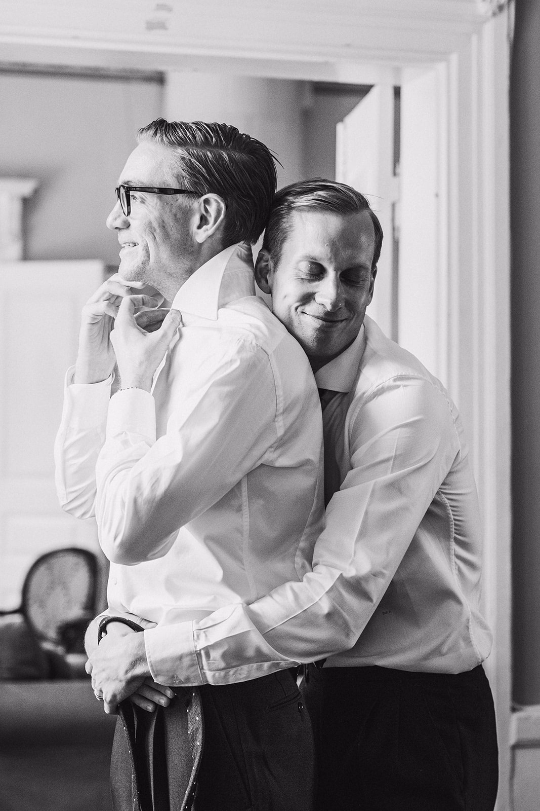 A friend helping the groom with his collar before the ceremony.