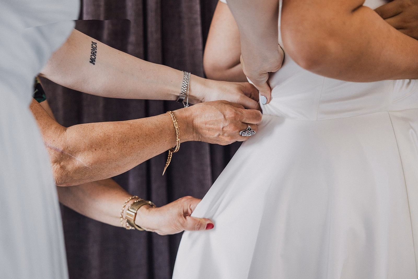 Hands fastening the bride’s wedding dress.