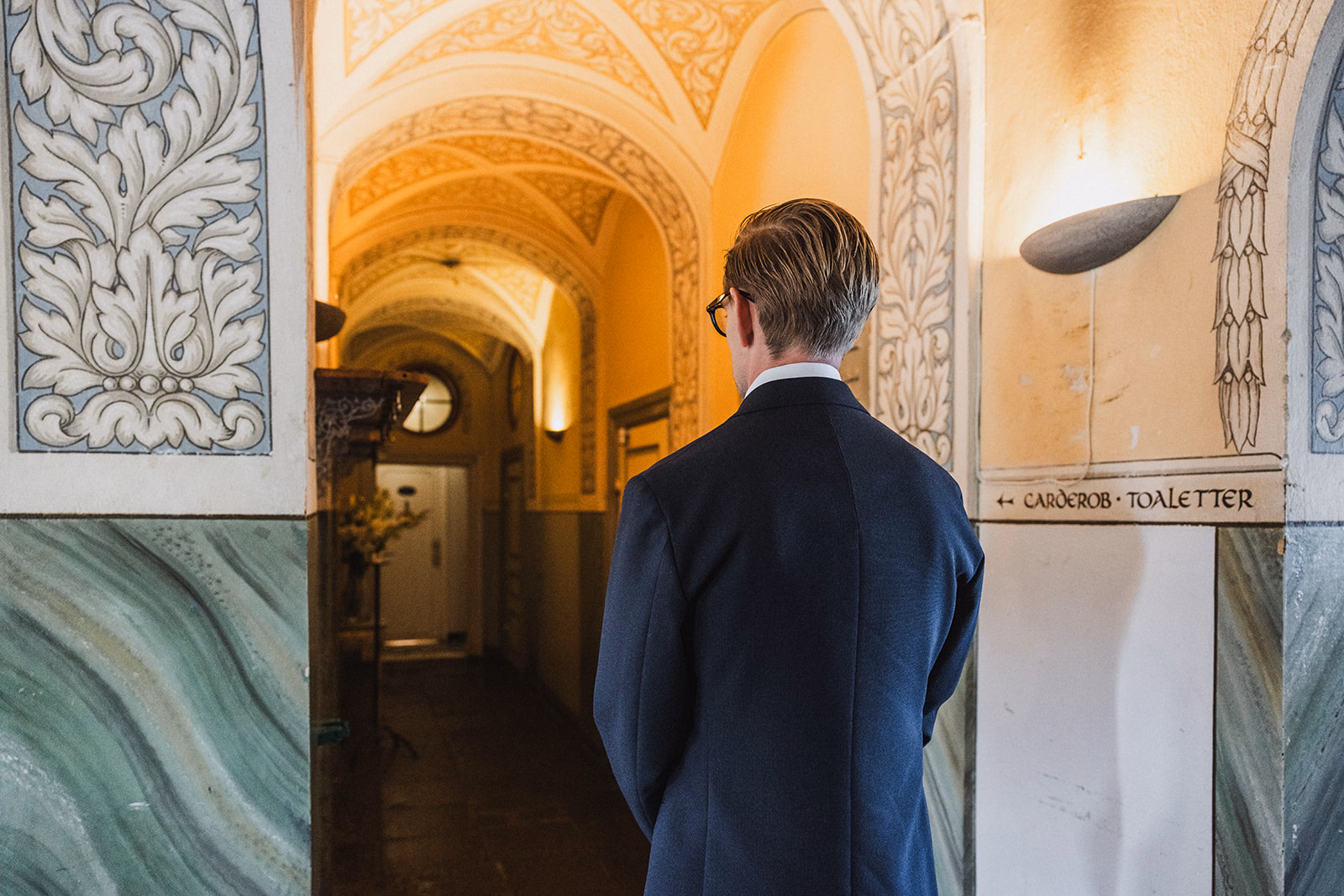 The groom waiting in an ornate hallway for the first look.
