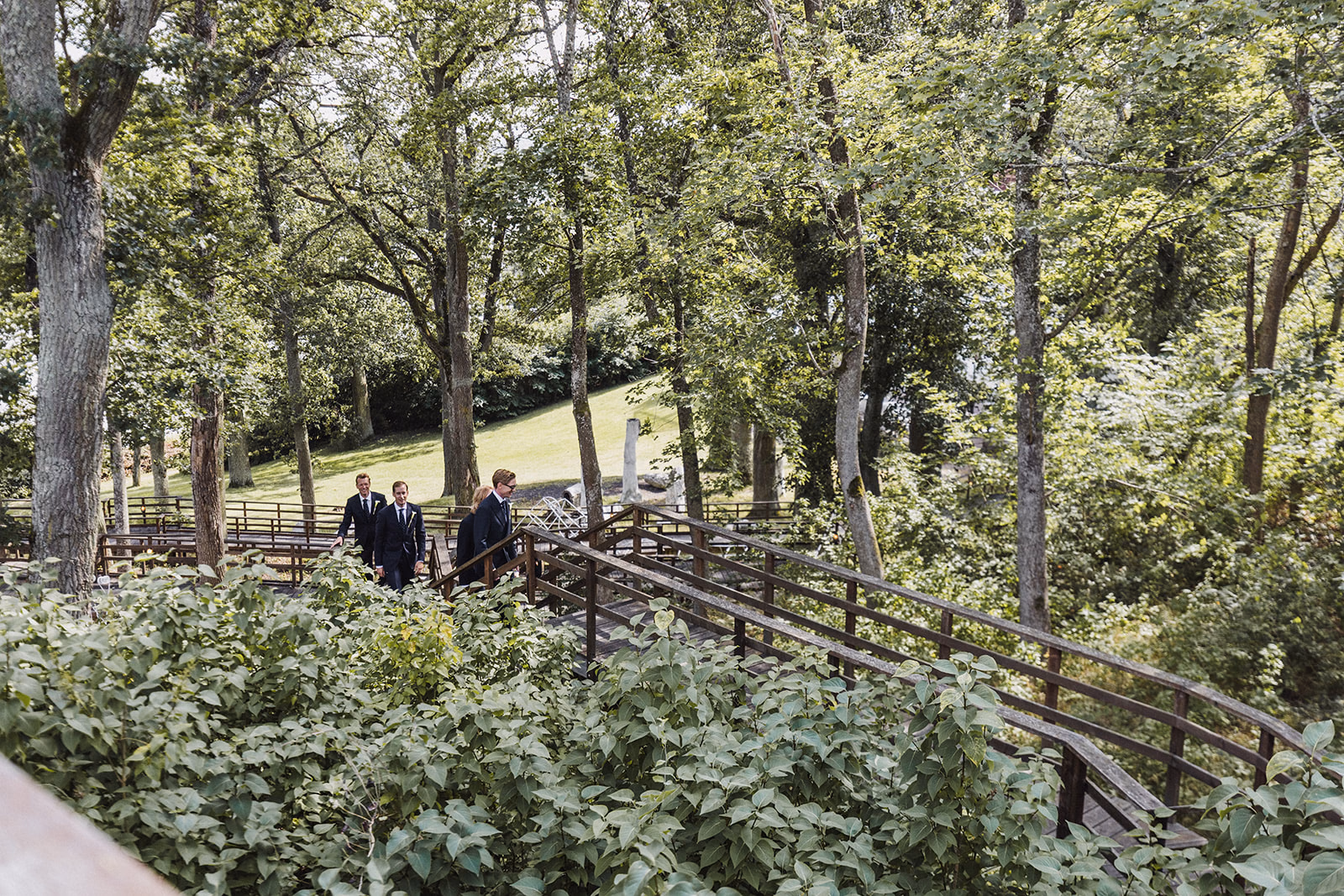 Wedding guests walking through the woods towards the outdoor ceremony.