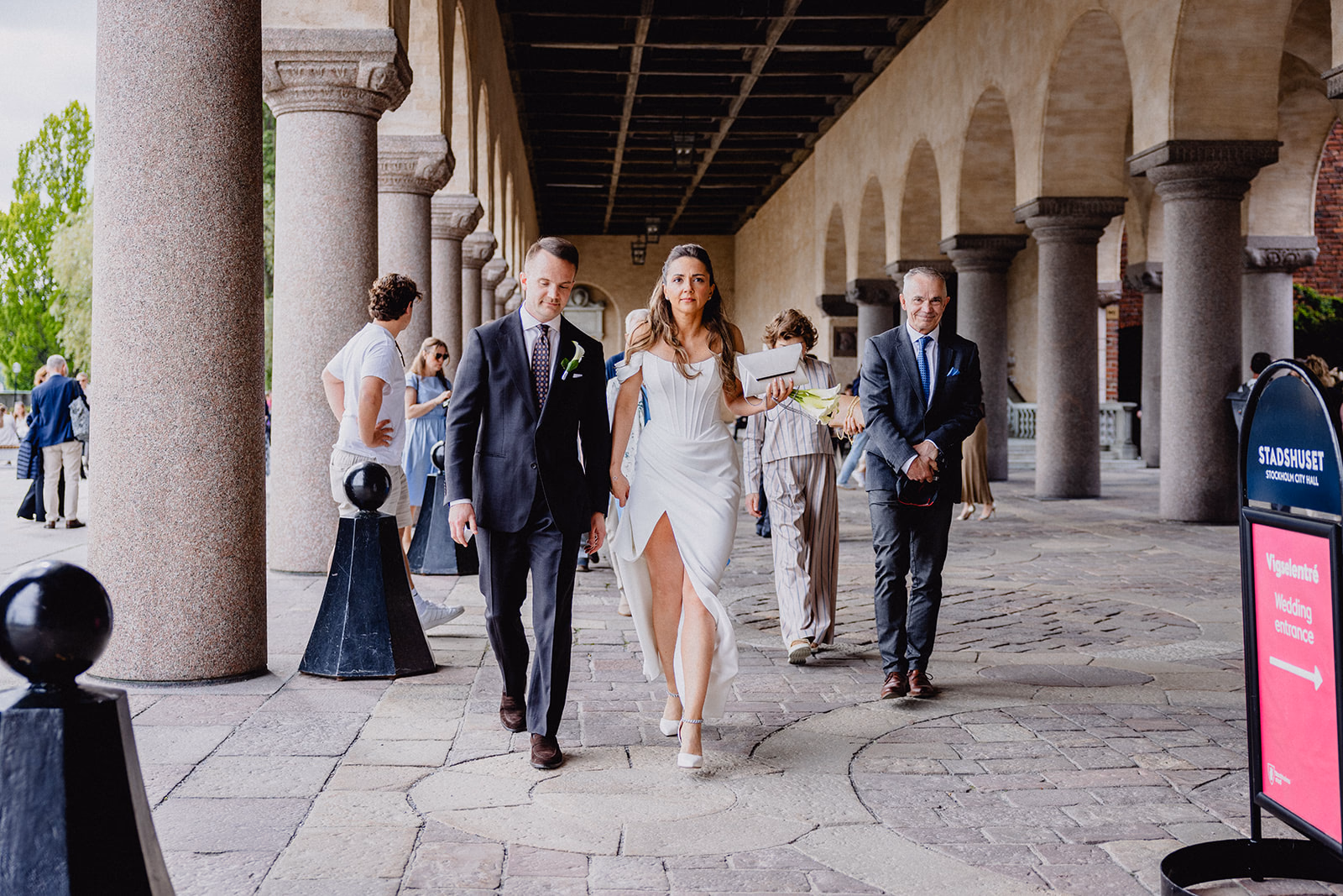 Gintare and Mikael walking with their guests beneath the Stockholm City Hall colonnade.