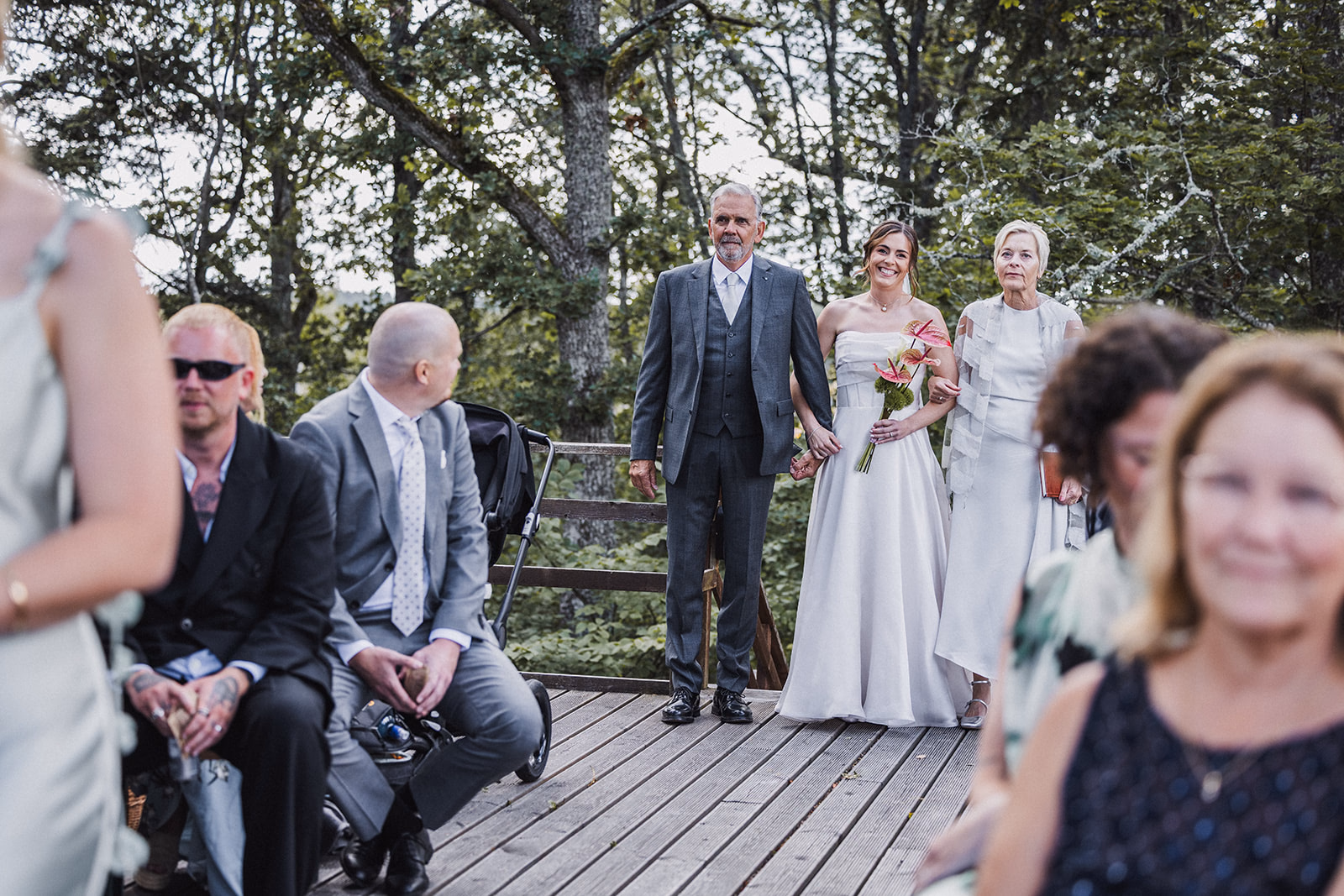 The bride arriving with her parents at the outdoor wedding ceremony.