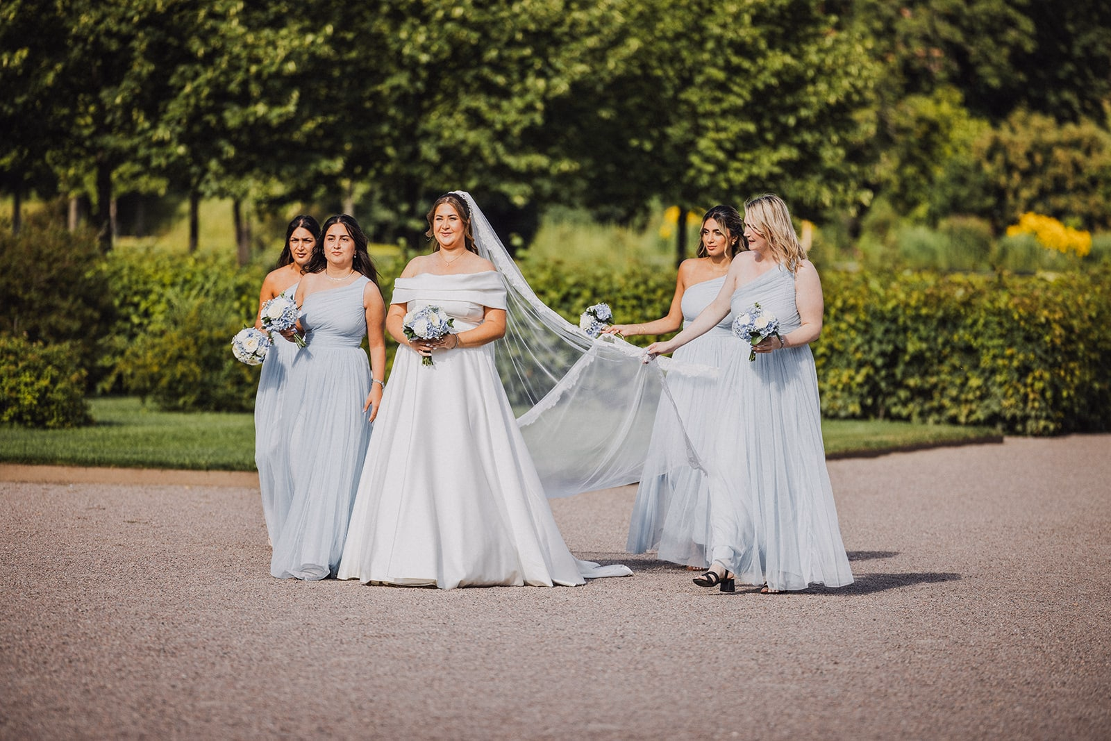 Bridesmaids walking together towards the outdoor ceremony.