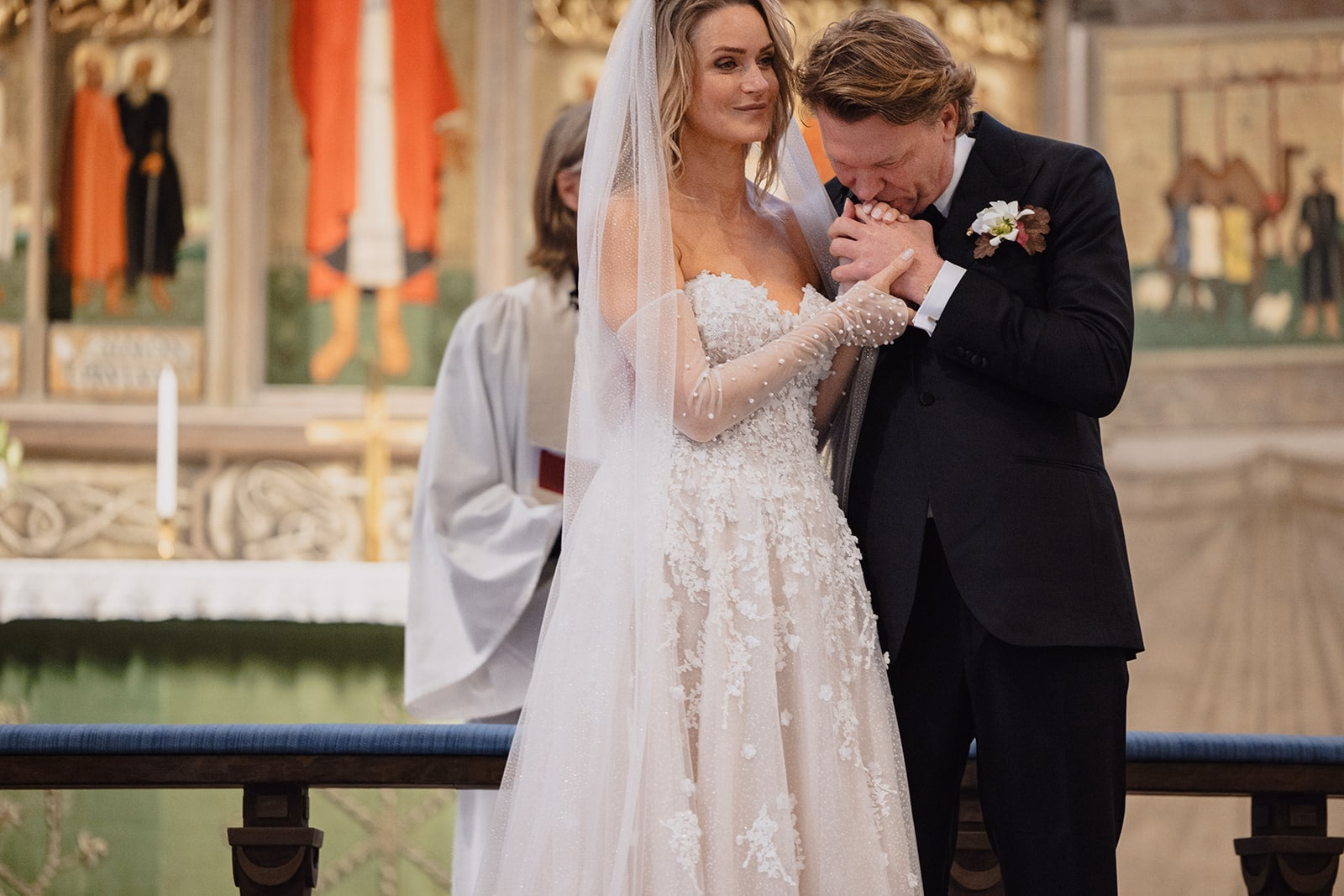 The groom kissing the bride’s hand during the wedding ceremony.