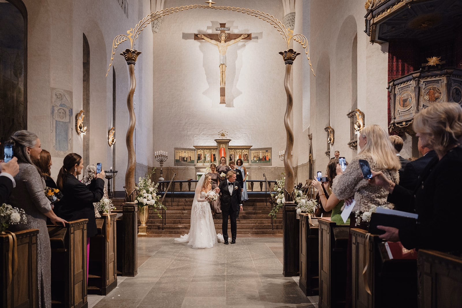 The newlyweds standing in the aisle before the altar at Högalidskyrkan.
