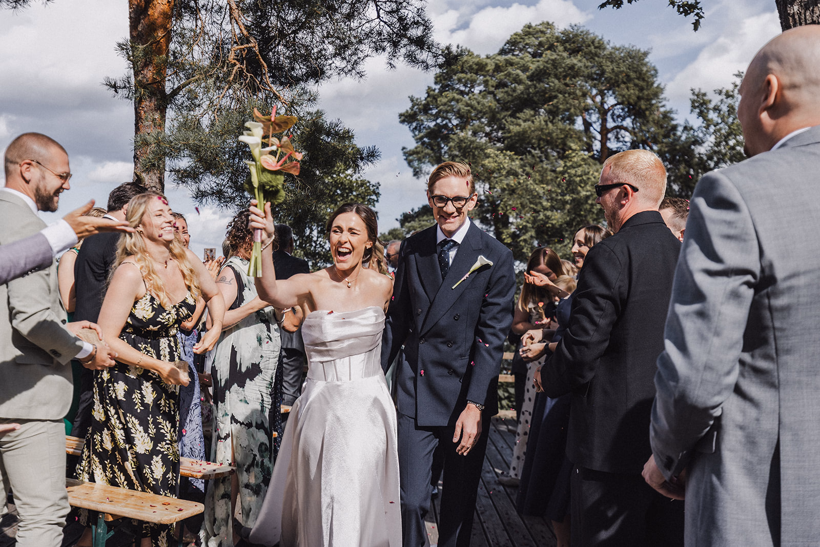 The newlyweds leaving the ceremony between cheering wedding guests.