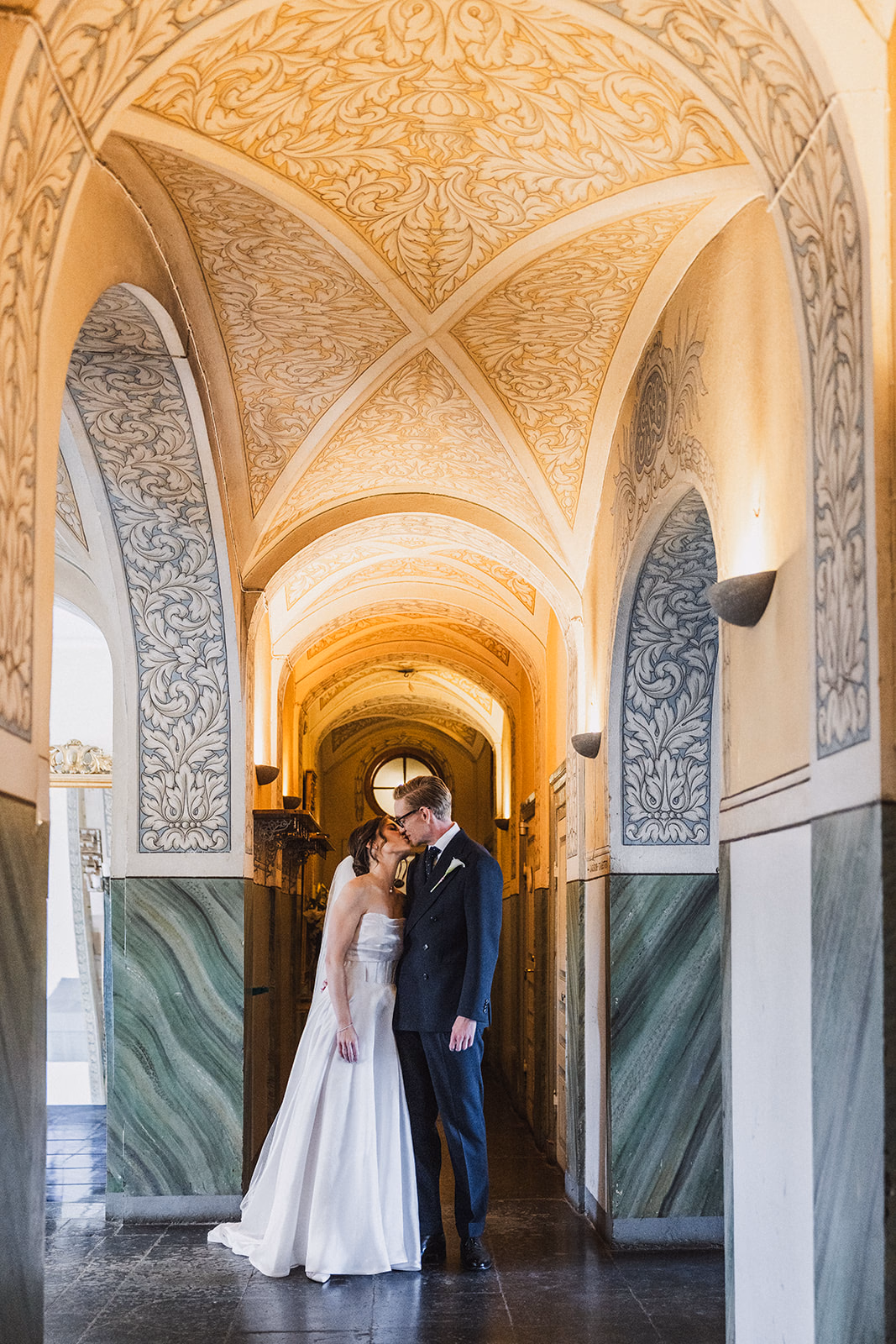 The newlyweds standing together in an ornate hallway at Ullvhälls Manor.