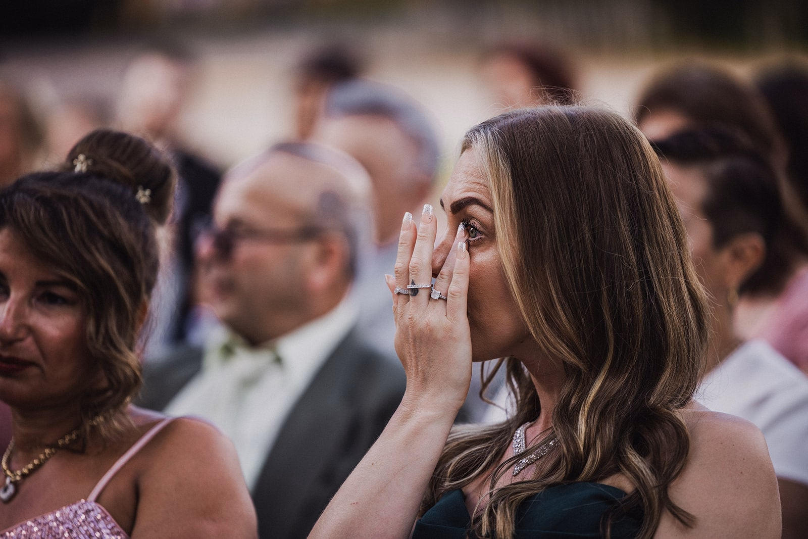 A wedding guest wiping away tears during the ceremony.