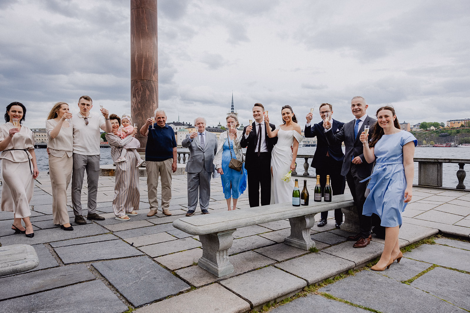 The wedding party raising a toast beside the water at Stockholm City Hall.
