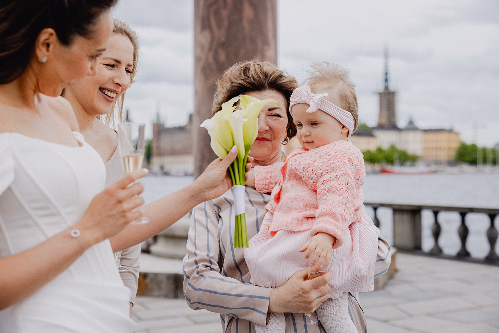 The bride sharing flowers with a young guest on the Stockholm City Hall terrace.