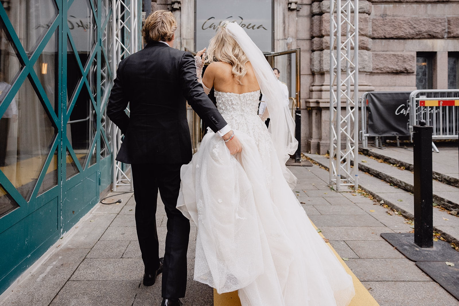The newlyweds walking together towards the entrance to Café Opera.
