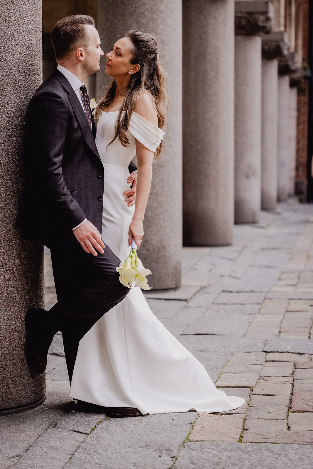 Gintare and Mikael facing one another beside the stone columns at Stockholm City Hall.