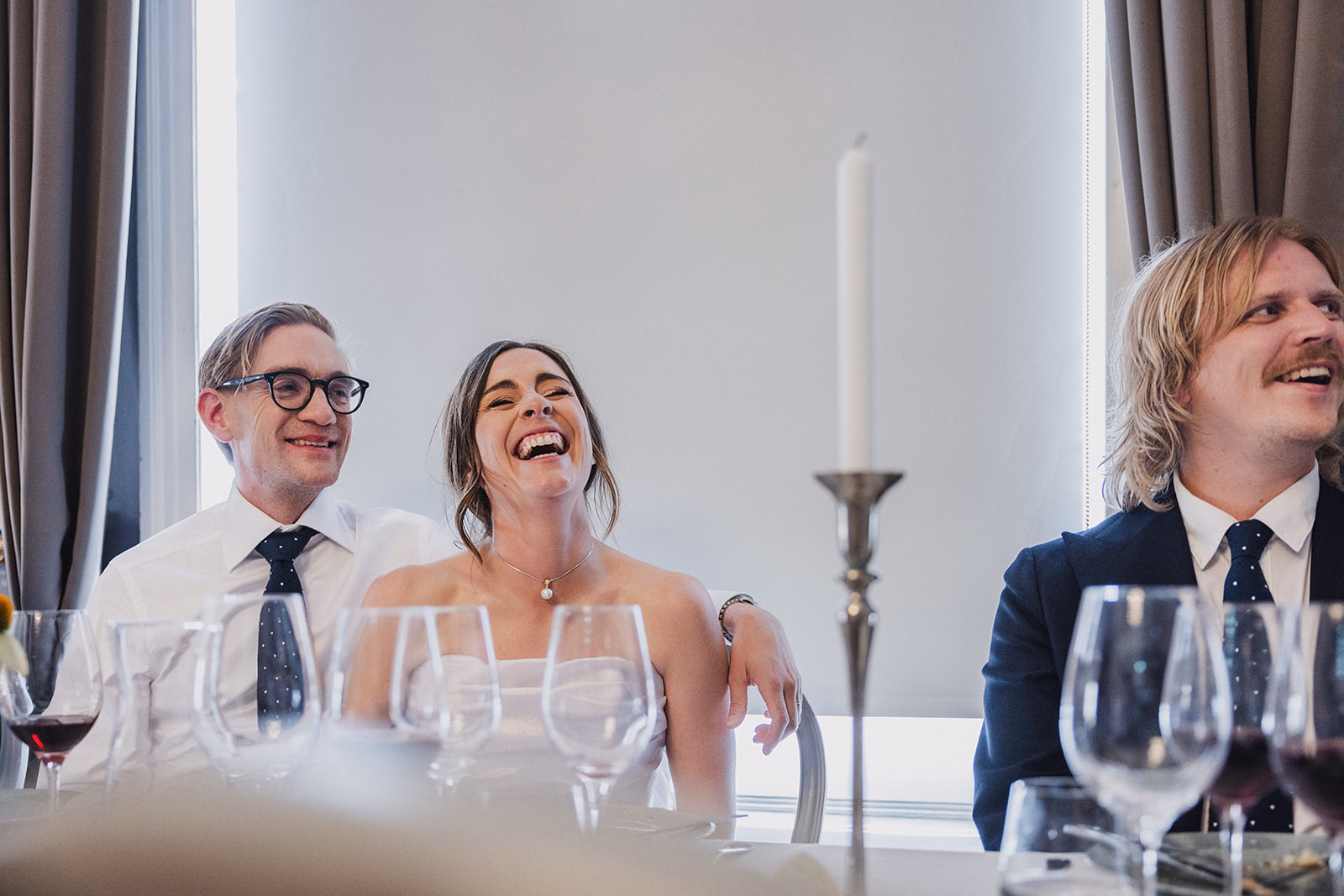 The newlyweds laughing together during a wedding speech.