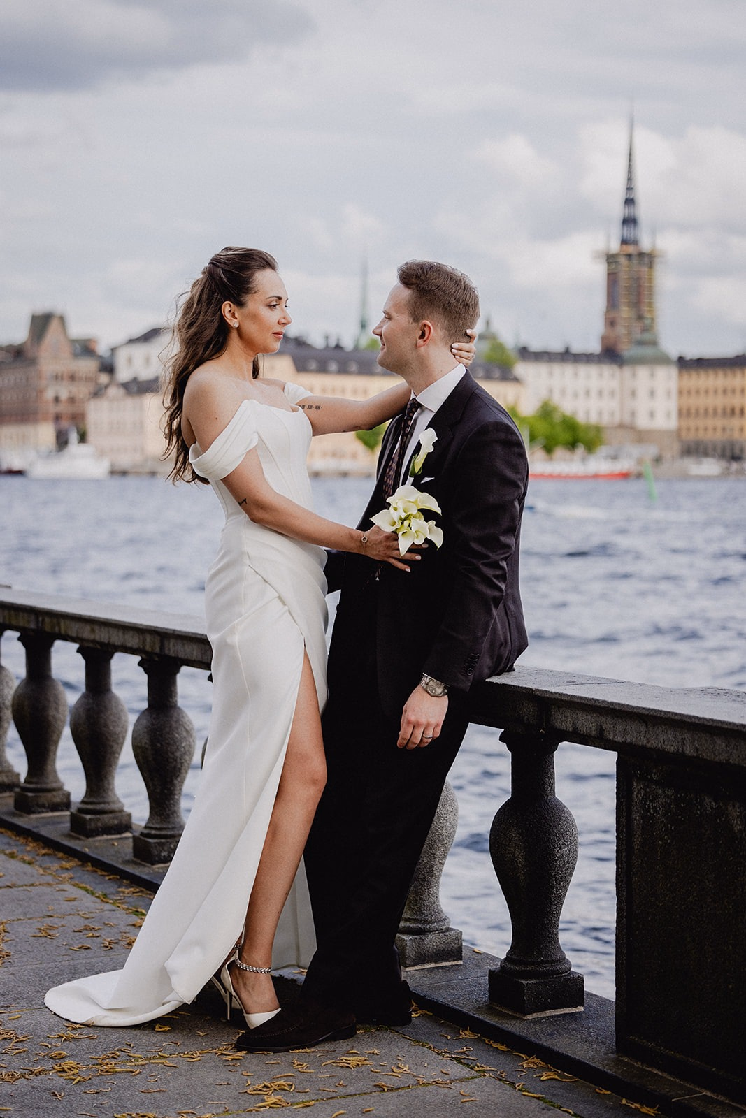 Gintare and Mikael looking at one another beside the water, with the Stockholm skyline behind them.