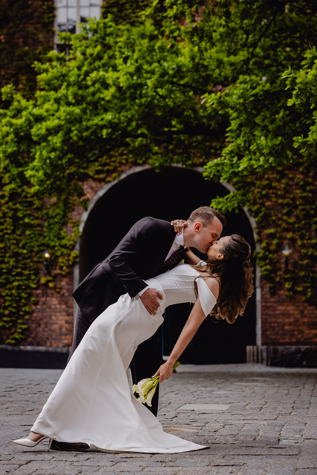Gintare and Mikael sharing a playful dip beneath an ivy-covered arch at Stockholm City Hall.