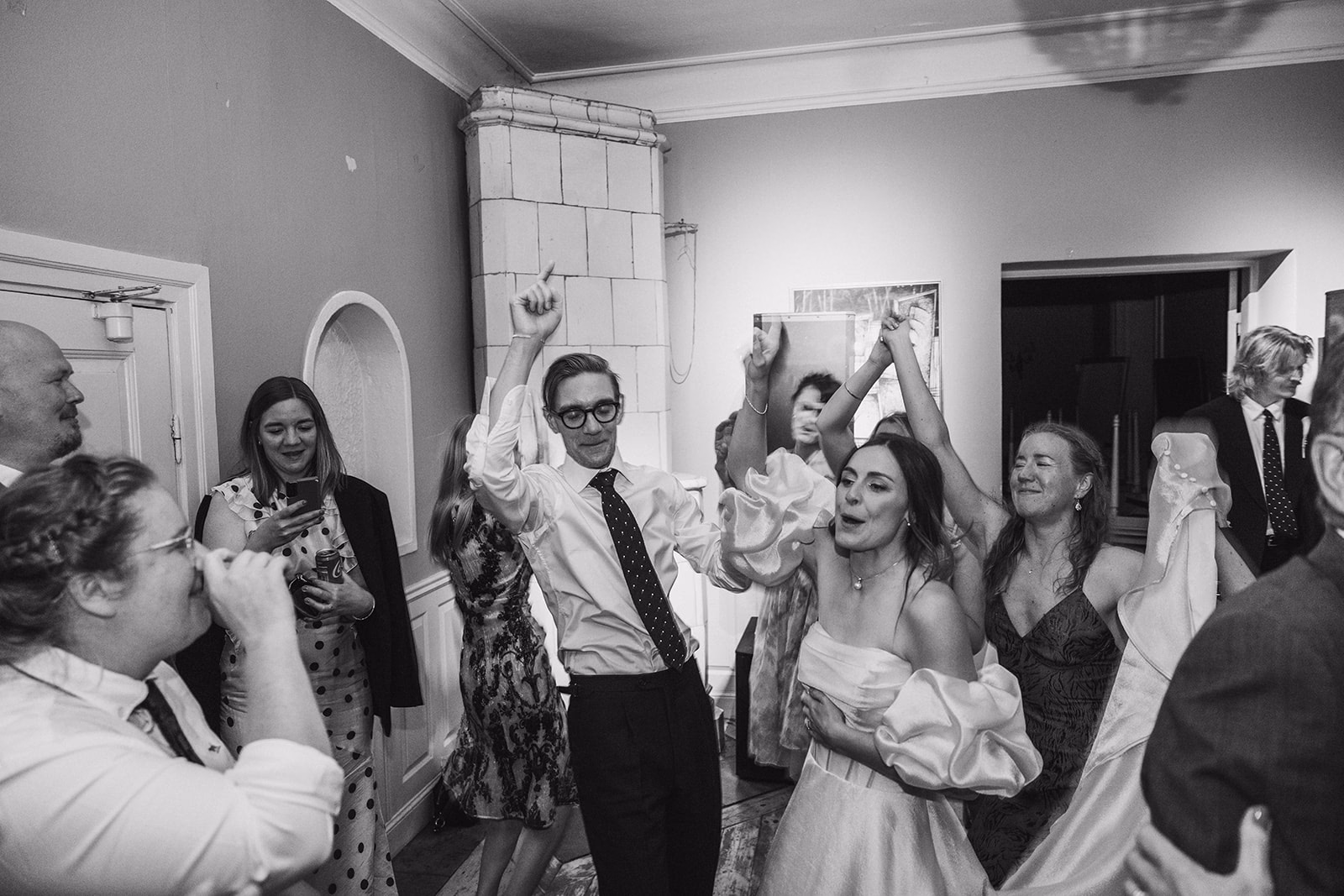 The groom dancing with wedding guests in black and white.