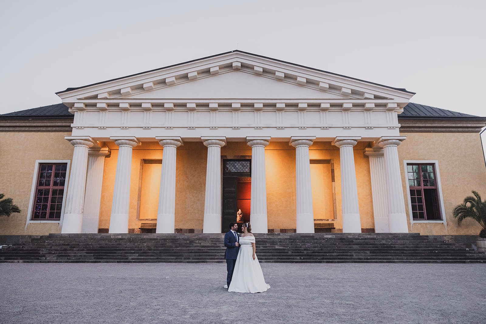 Sara and Kamran standing before the illuminated Linneanum at dusk.