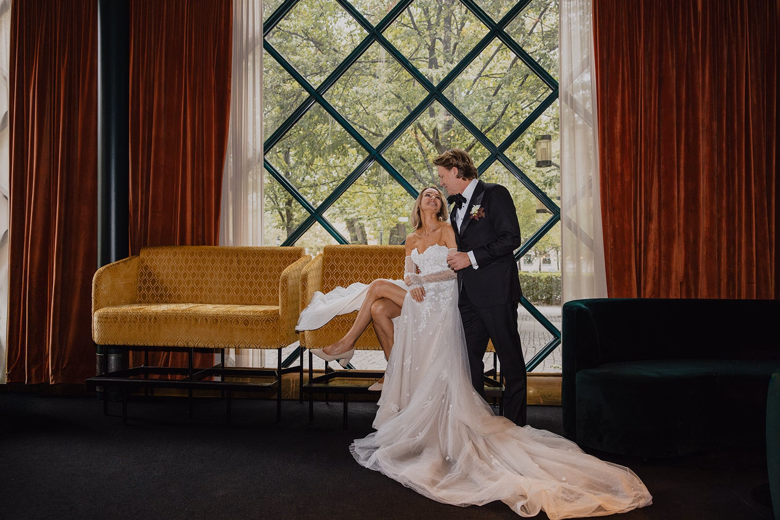 The newlyweds posing together beside the tall windows at Café Opera.