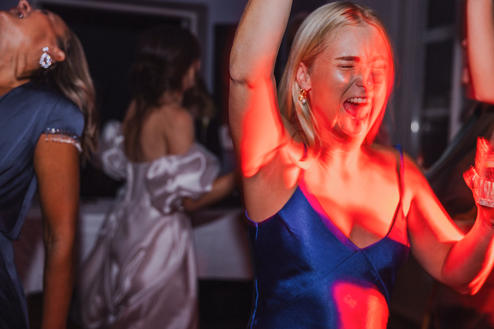 A wedding guest dancing beneath red party lights.
