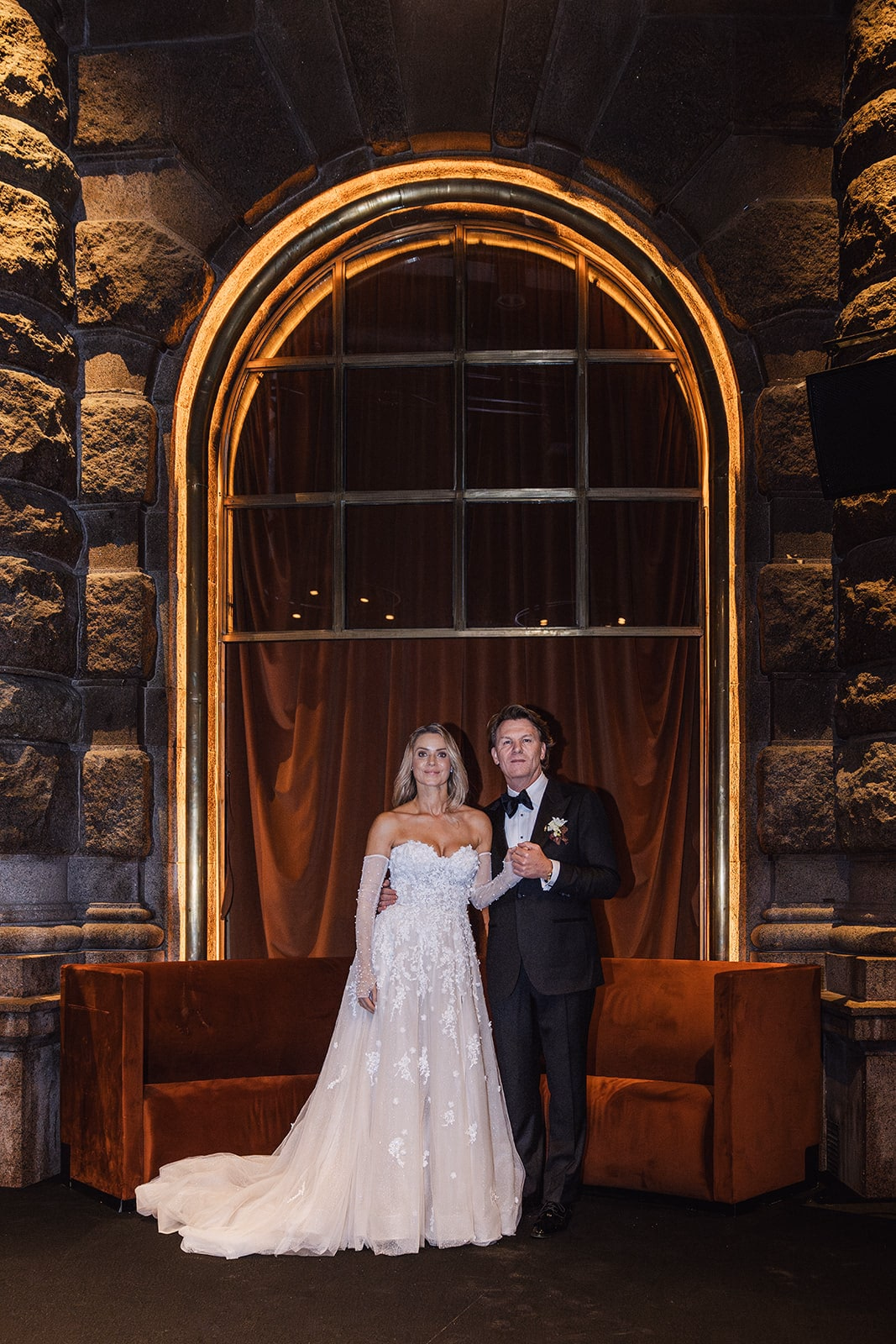 The newlyweds posing beneath an arched window inside Café Opera.