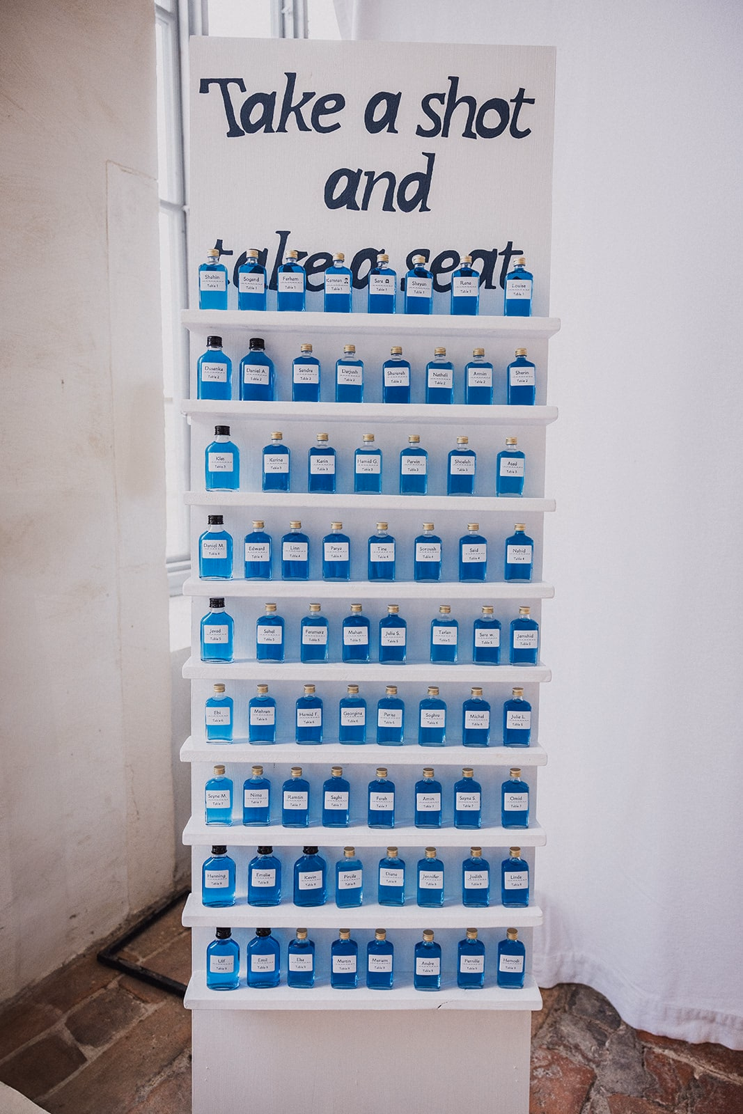 A reception welcome display with small blue bottles for the guests.