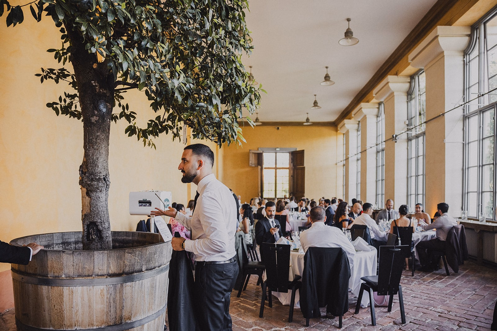 The wedding dinner room filled with guests beneath the indoor trees.