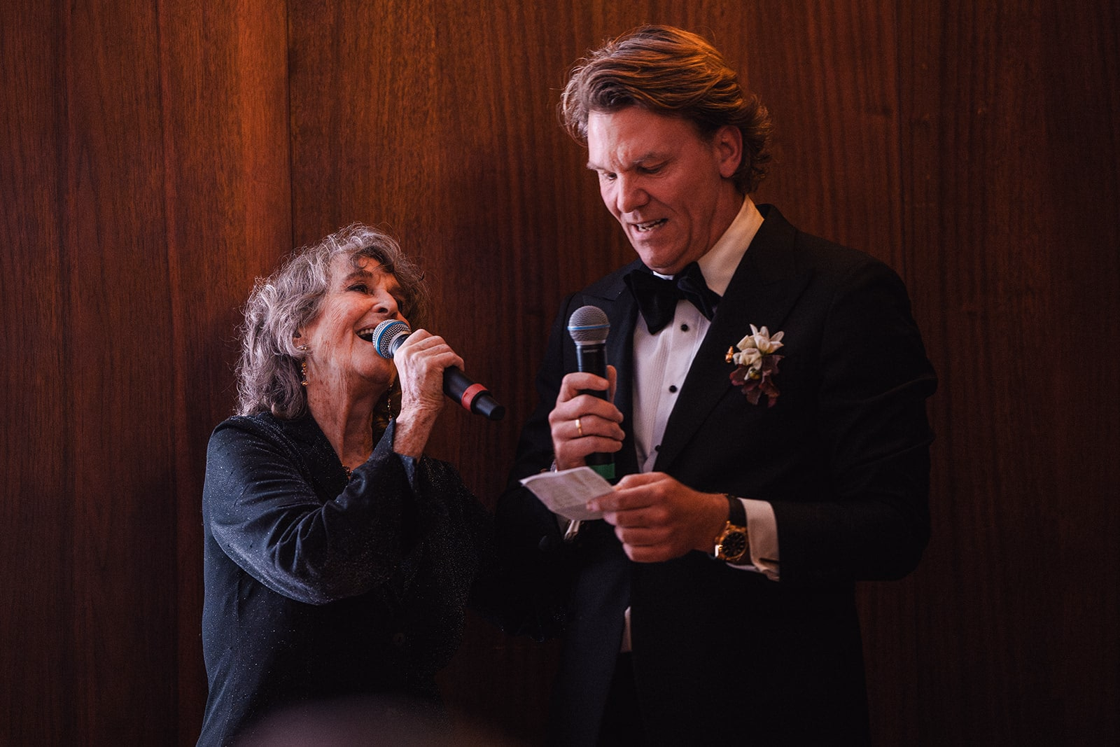 A guest speaking beside the groom during the wedding dinner.