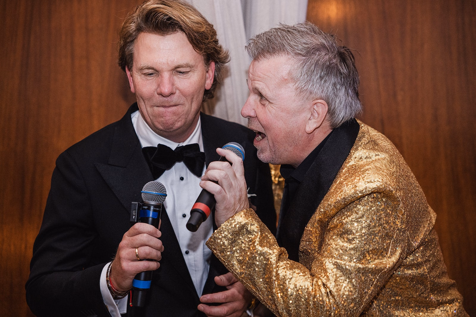 An entertainer in a gold jacket performing beside the groom.