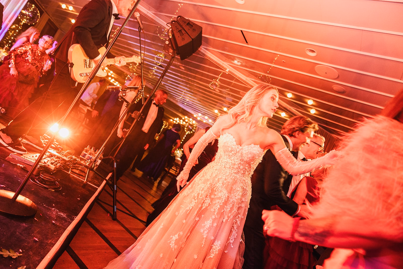 The bride dancing with guests beneath red party lights.