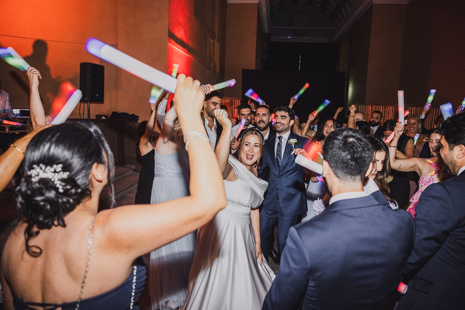 Wedding guests dancing together with glow sticks.