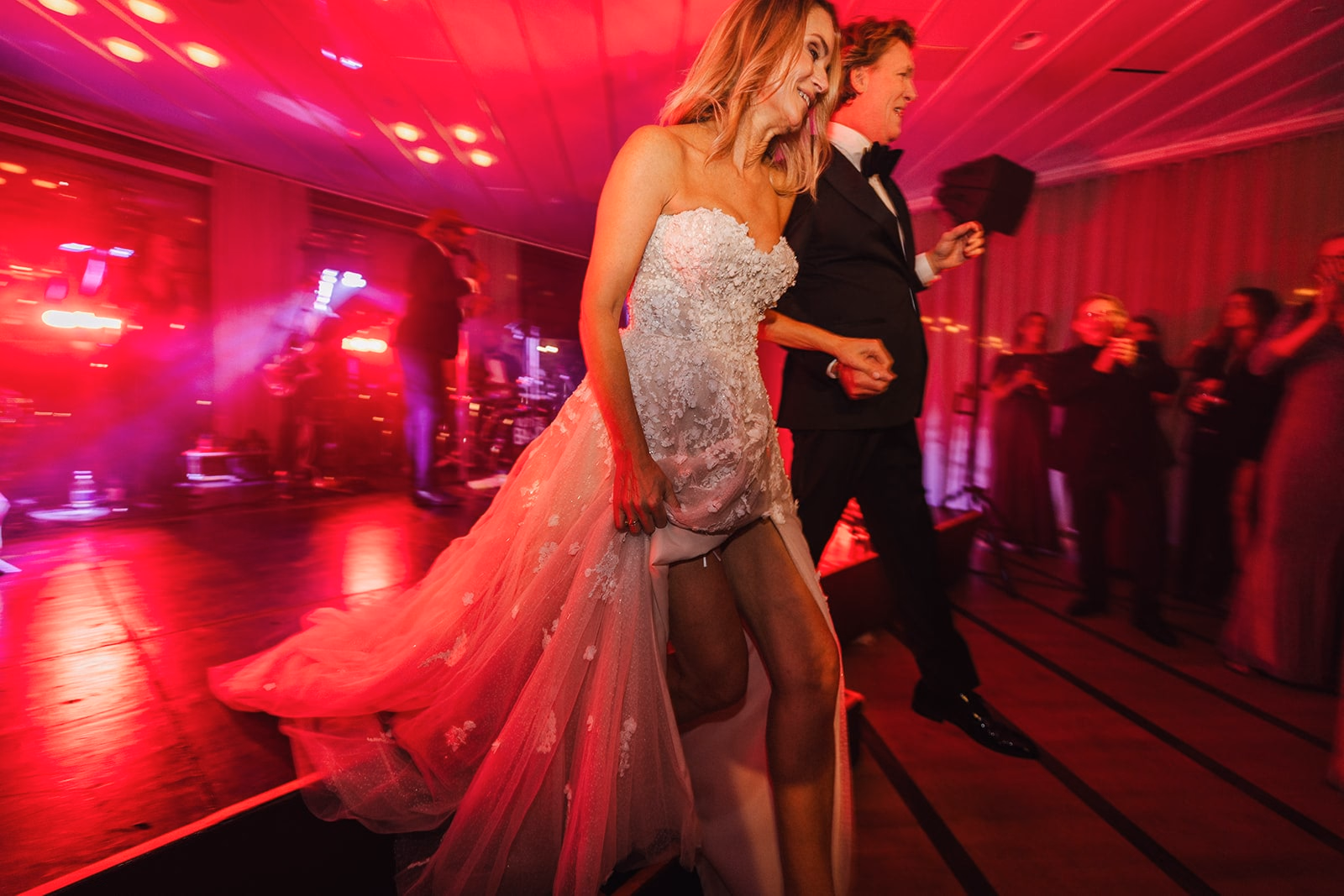 Vanessa and Jens moving through the dance floor together beneath red party lights.