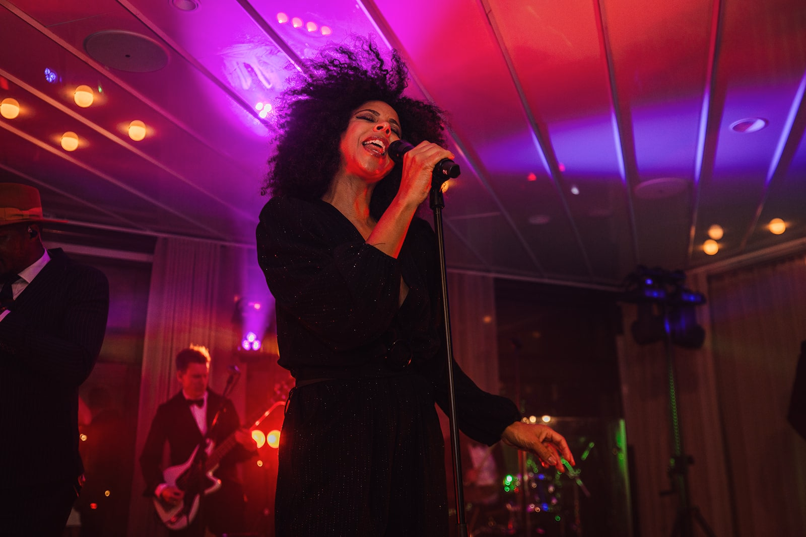 A live singer performing beneath red and violet stage lights at Café Opera.