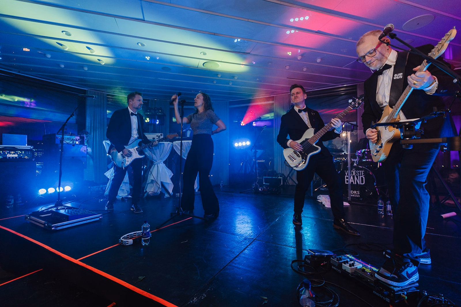 The live band performing beneath blue and magenta lights at Café Opera.