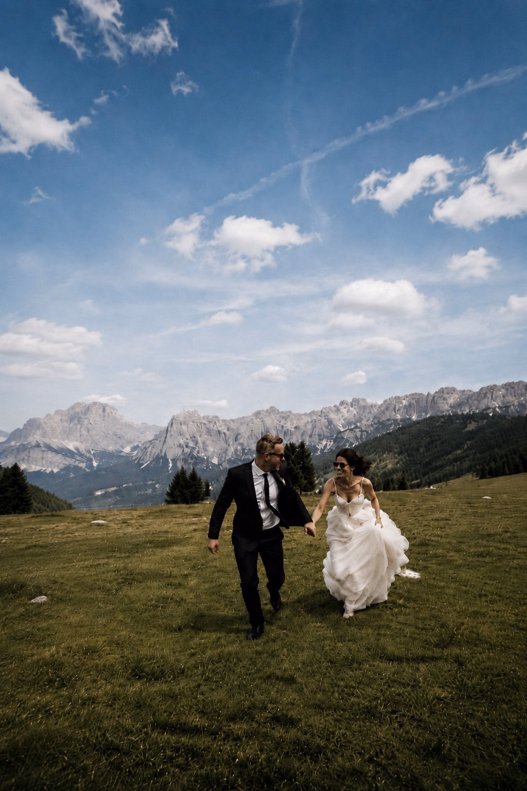 Gli sposi passeggiano insieme in un prato di montagna.