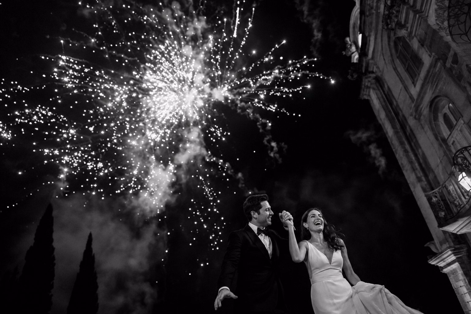Gli sposi guardano i fuochi d’artificio davanti a un edificio storico.