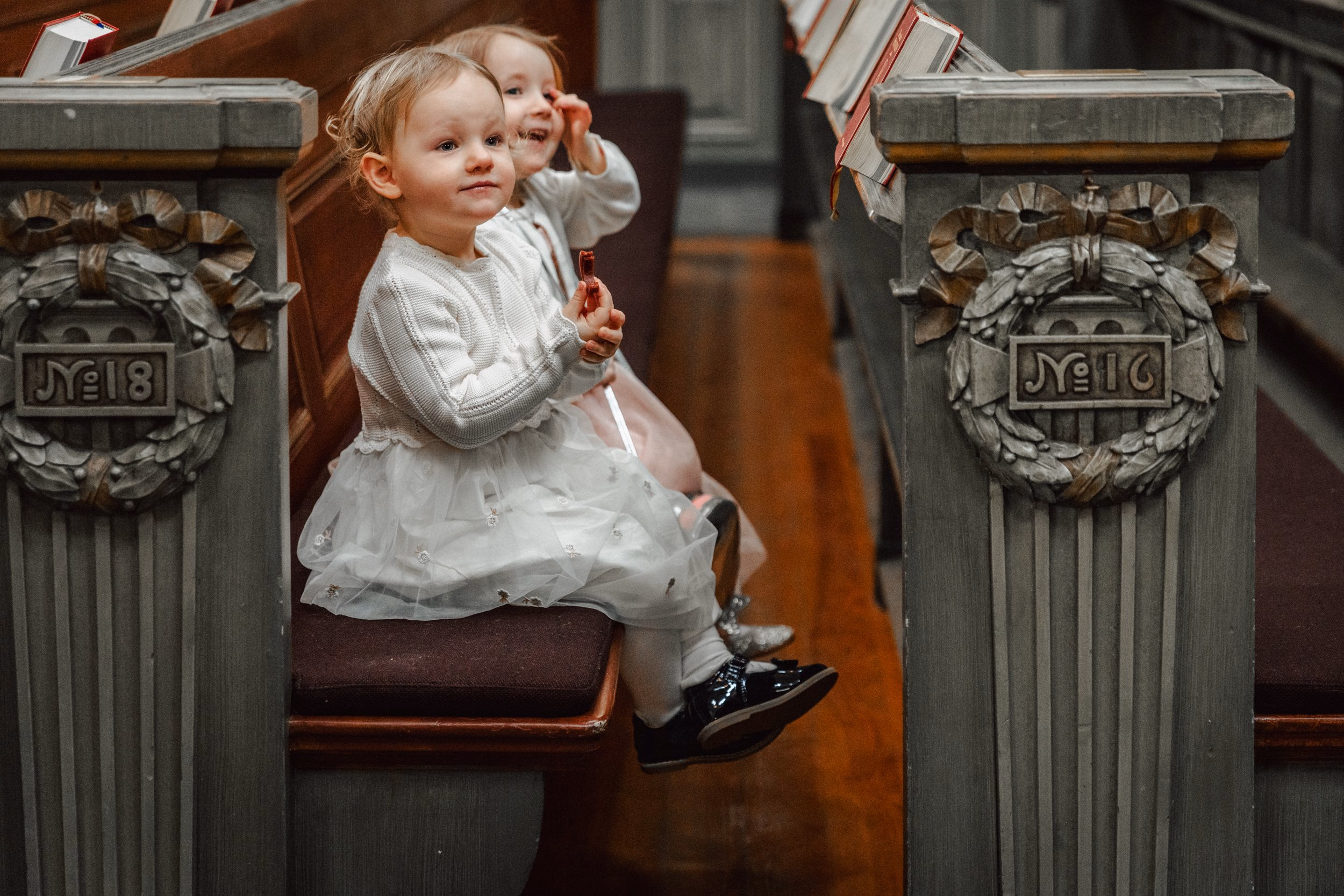 Un bambino seduto tra i banchi intagliati di una chiesa.