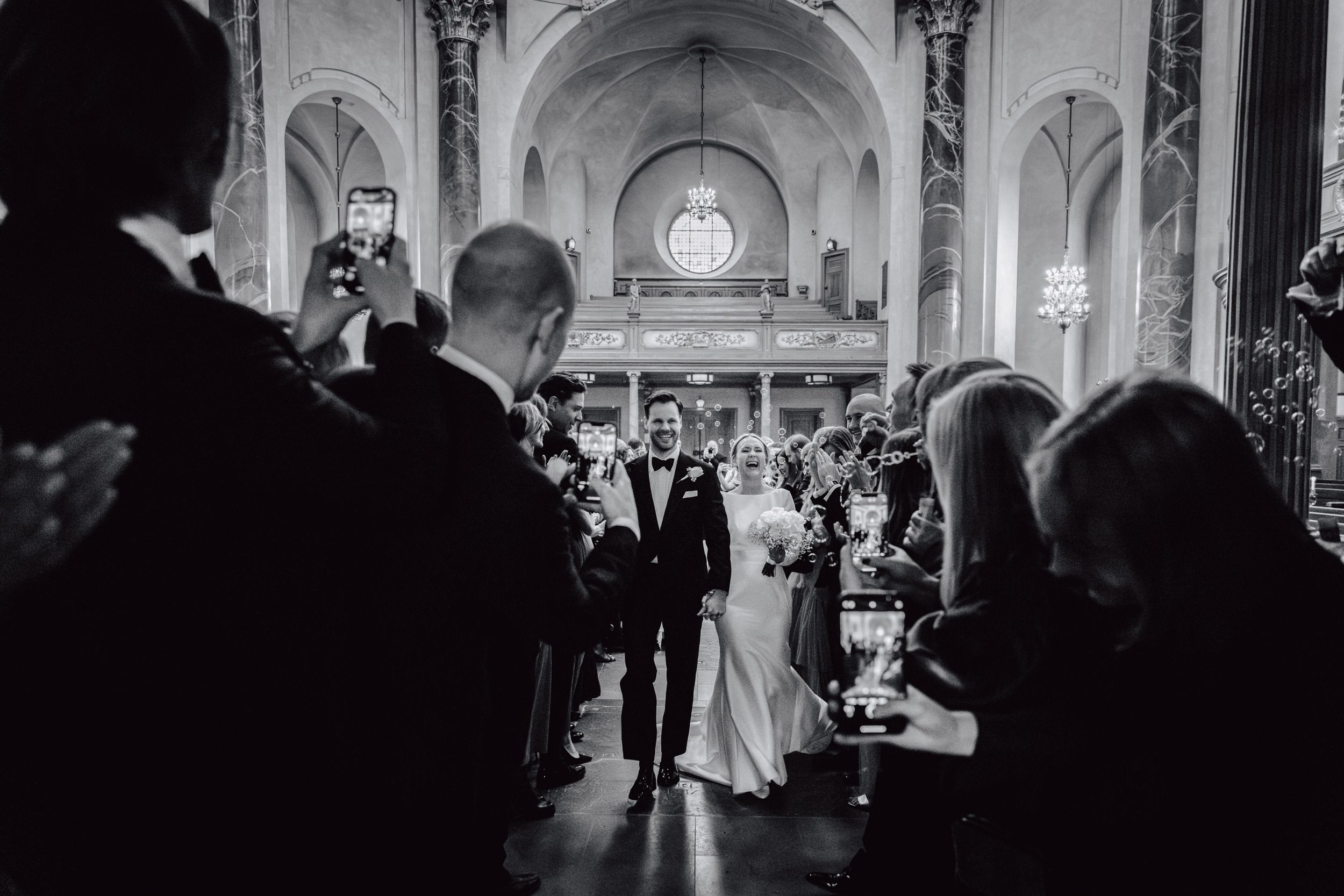 Una cerimonia in chiesa vista da dietro gli invitati, in bianco e nero.