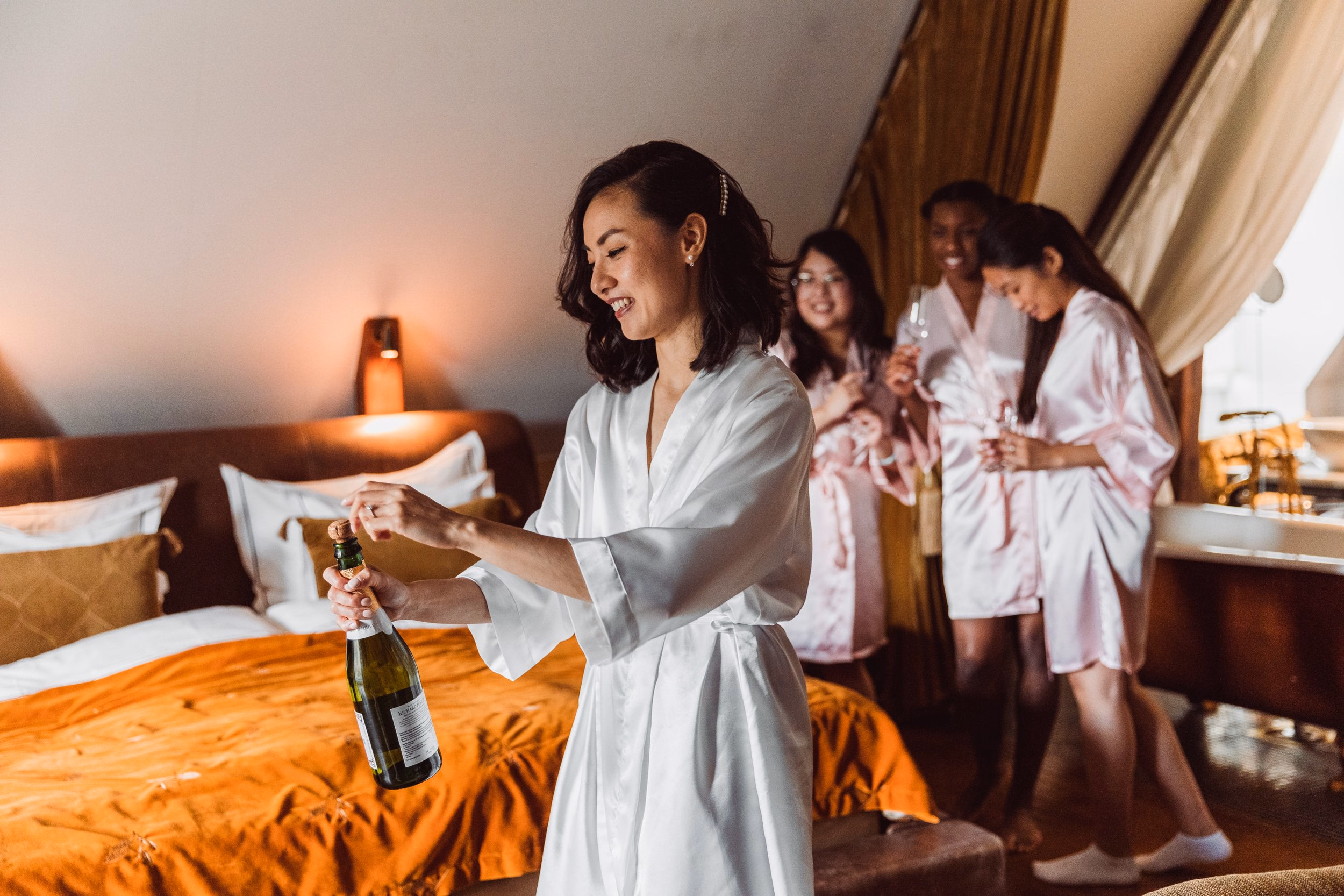La sposa apre una bottiglia di champagne con le damigelle.