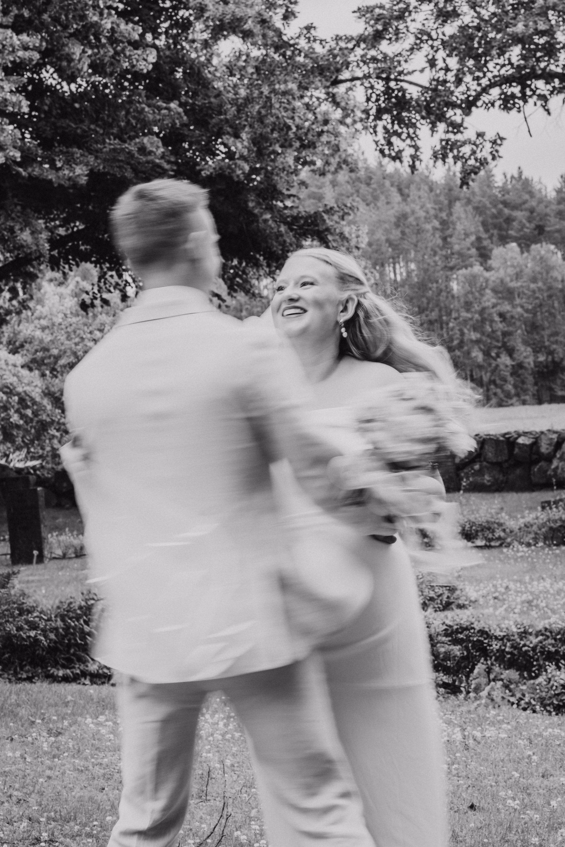 Gli sposi ballano all’aperto in una fotografia mossa in bianco e nero.