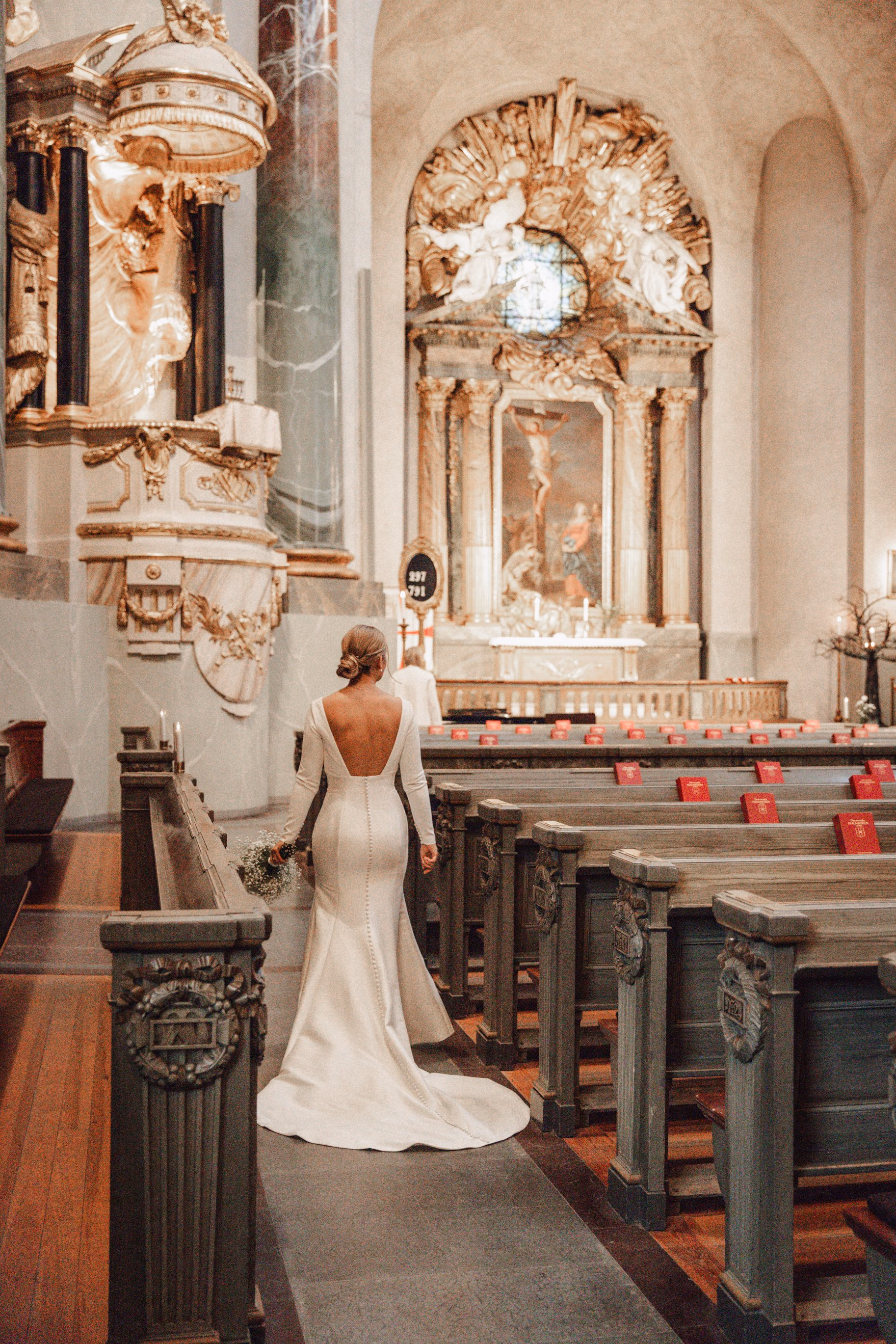 La sposa da sola accanto all’altare decorato di una chiesa.