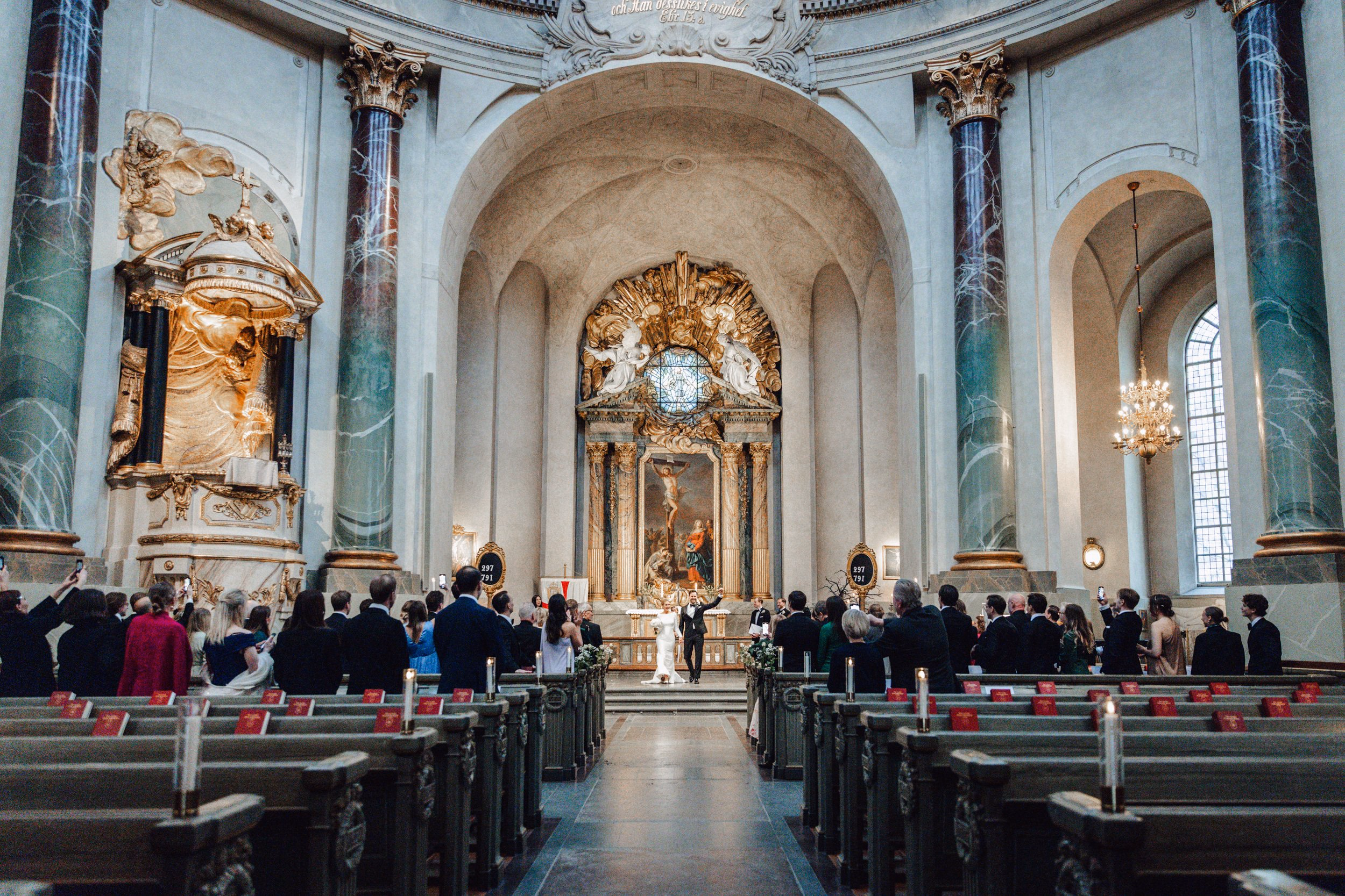 Veduta ampia degli invitati seduti durante una cerimonia in chiesa.