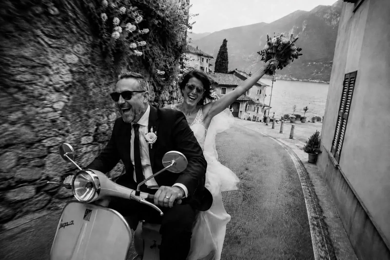 Una coppia appena sposata in Vespa accanto a un lago del Nord Italia.