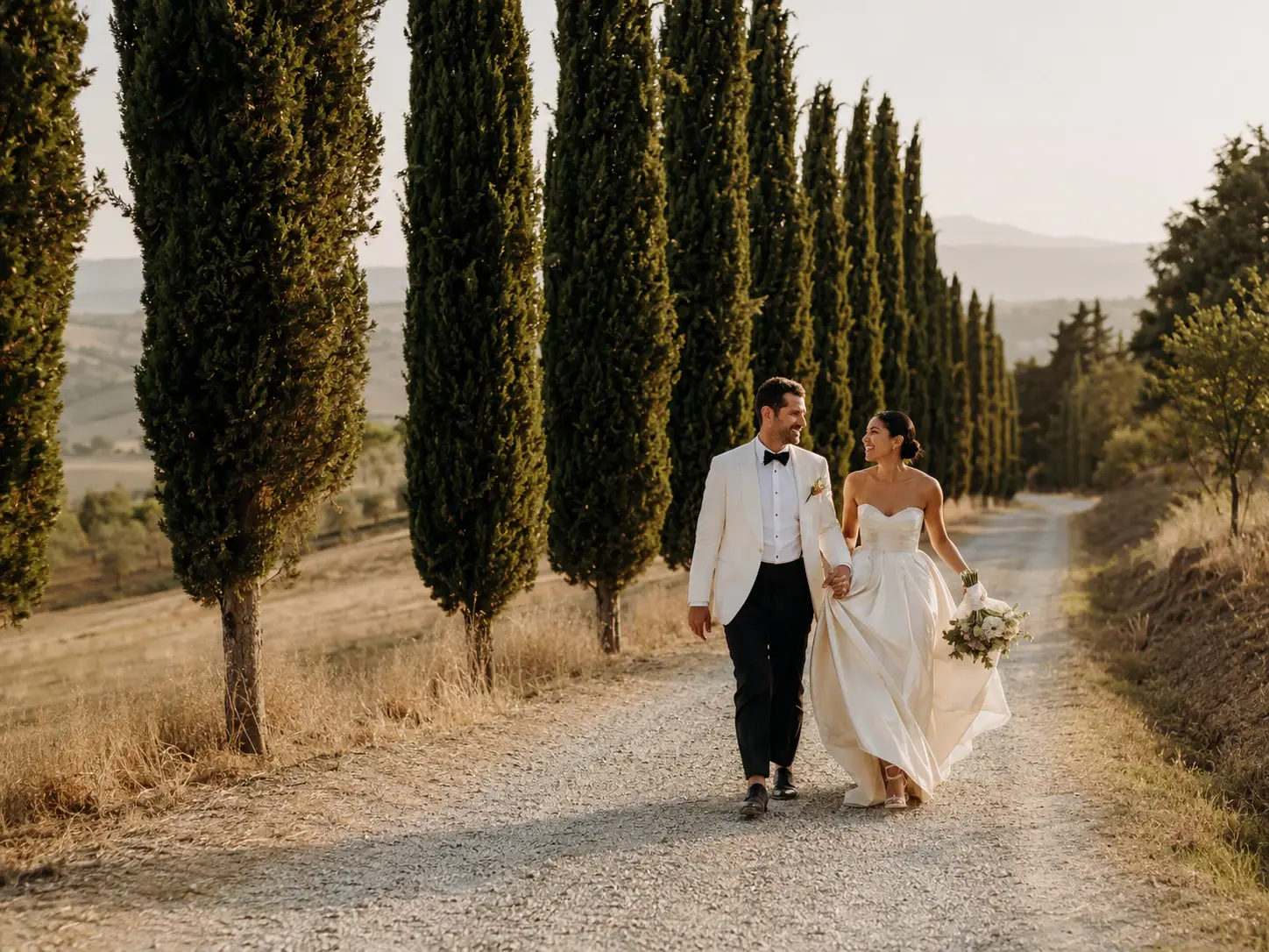 Bride and groom walking along the iconic cypress-lined road at Borgo Stomennano in Tuscany during a romantic destination wedding.