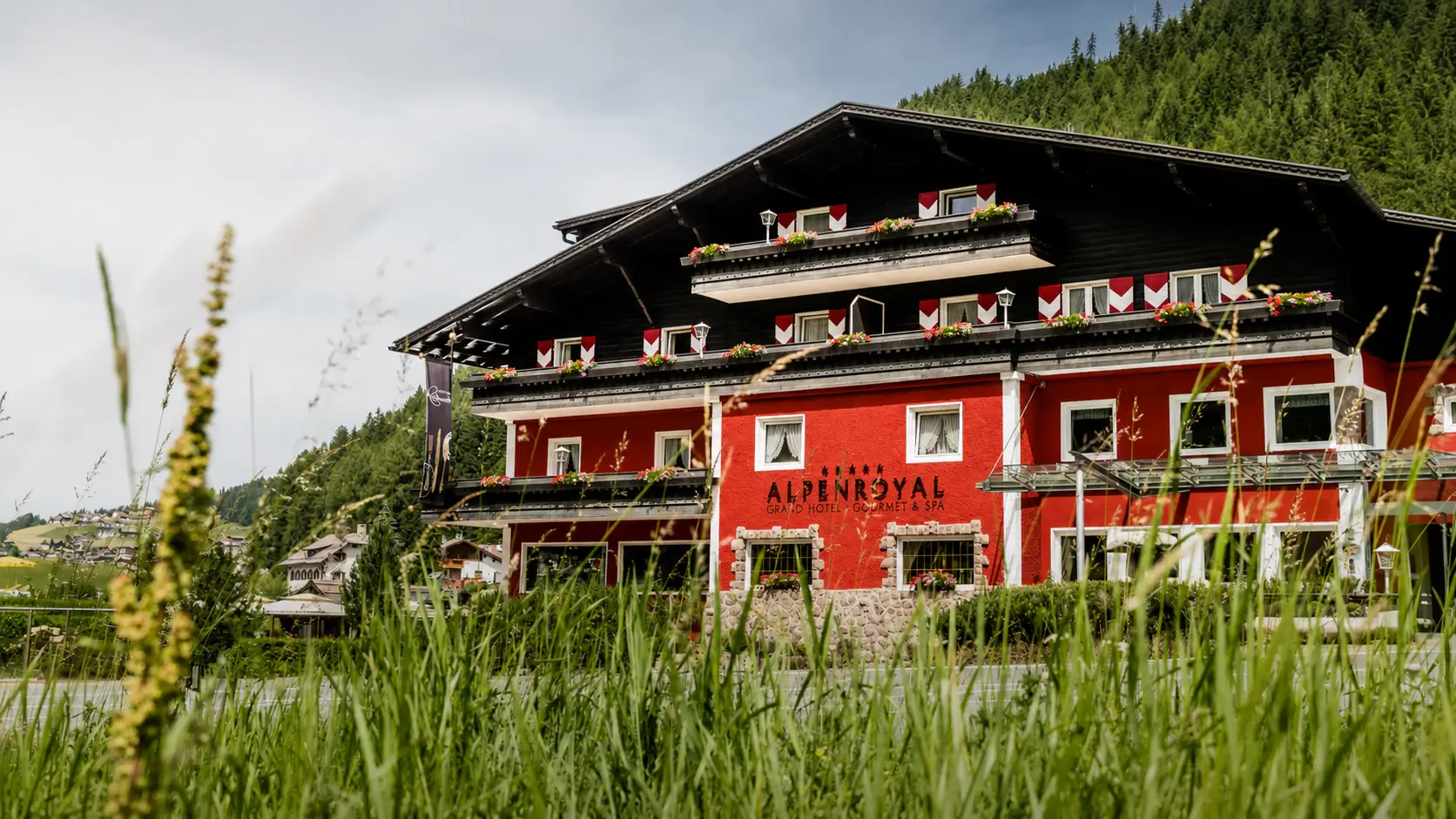 Red alpine hotel beneath mountain peaks.