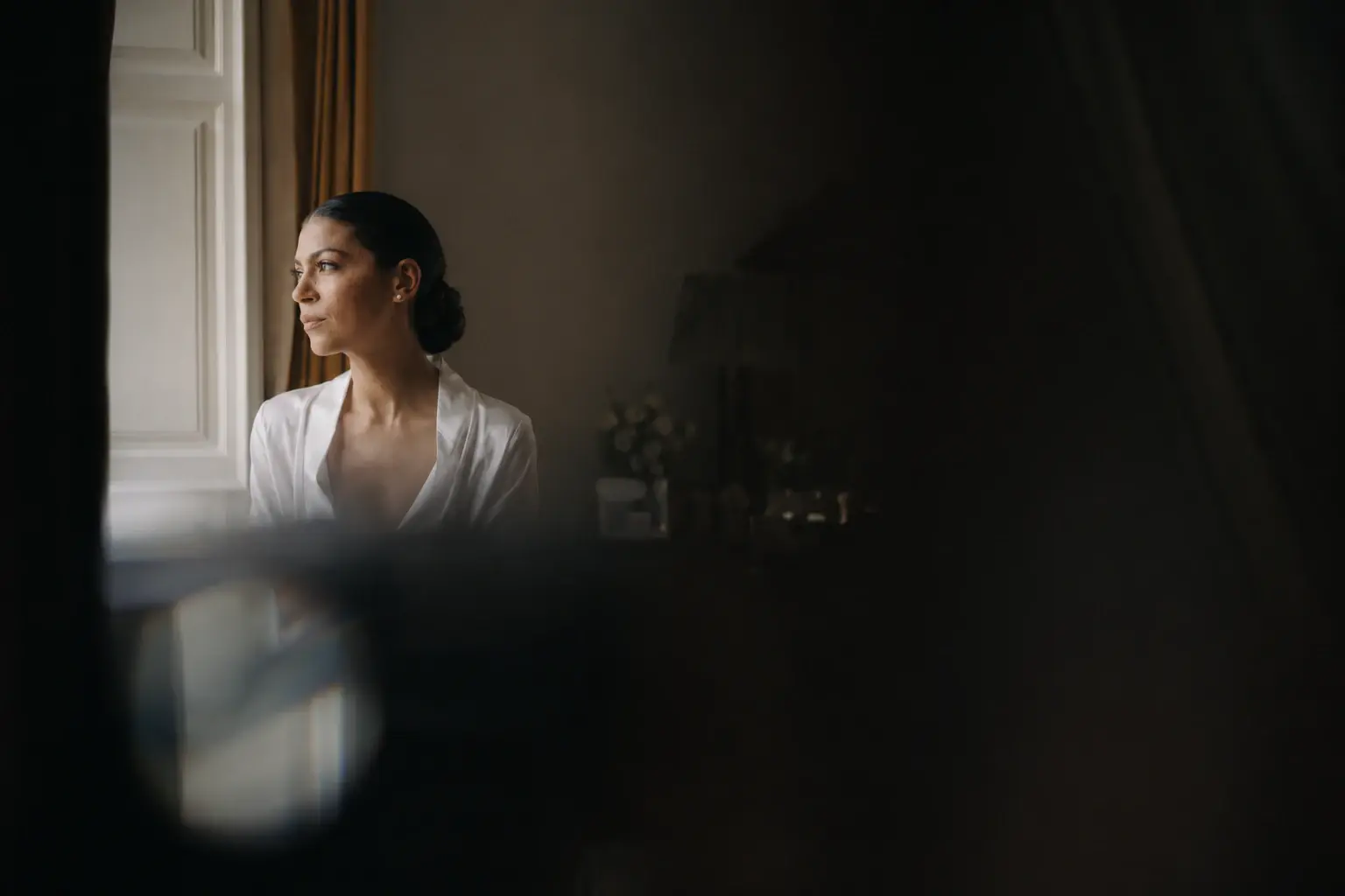 Bride standing beside a window during wedding preparations at Villa Cetinale.